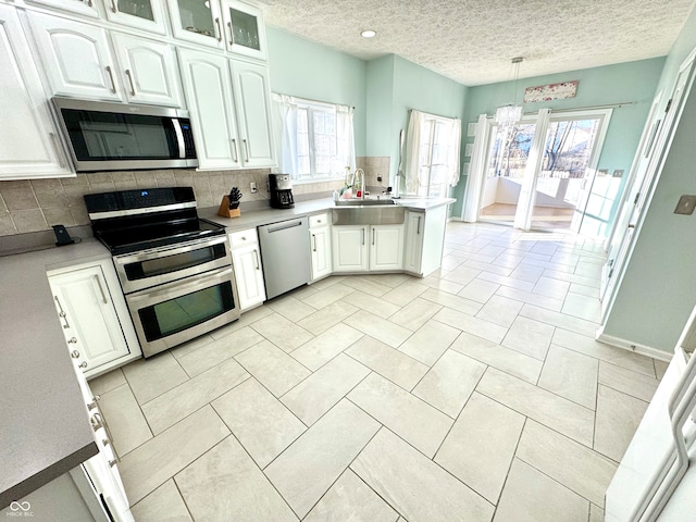 kitchen with stainless steel appliances, a peninsula, decorative backsplash, and white cabinets