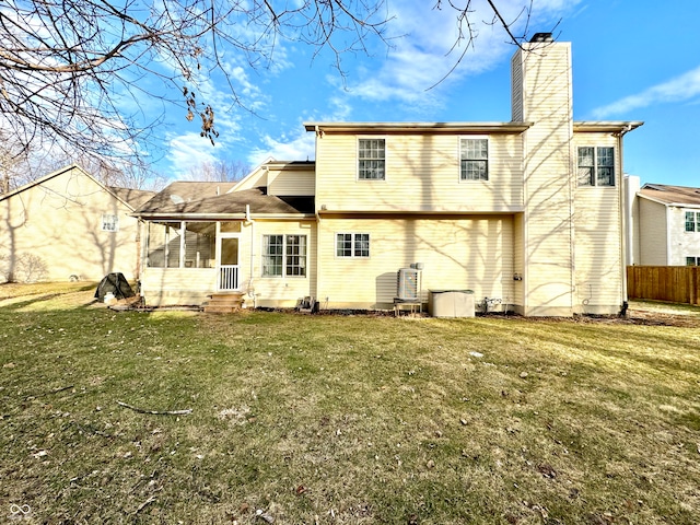 rear view of property with a sunroom, a chimney, fence, and a lawn