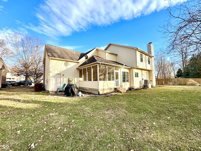 rear view of property with entry steps, fence, a sunroom, a lawn, and a chimney