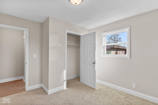 unfurnished bedroom featuring a closet, light colored carpet, and baseboards