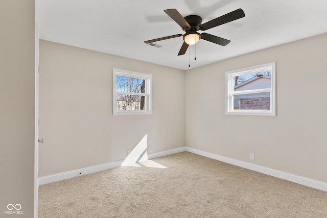 carpeted spare room with baseboards, ceiling fan, and a healthy amount of sunlight