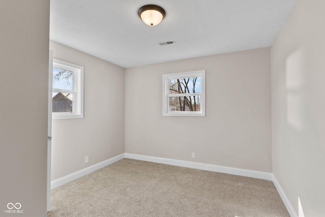 spare room featuring baseboards, visible vents, and carpet flooring