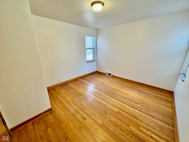 unfurnished room featuring light wood-type flooring, visible vents, and baseboards