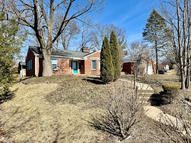 ranch-style home featuring brick siding and a chimney