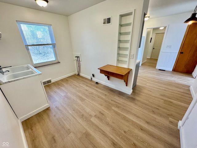 laundry room featuring baseboards, a sink, visible vents, and light wood-style floors