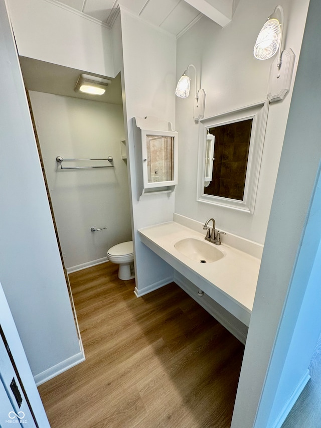 bathroom with baseboards, a sink, toilet, and wood finished floors