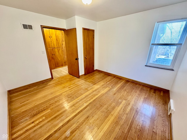 spare room with light wood finished floors, baseboards, and visible vents