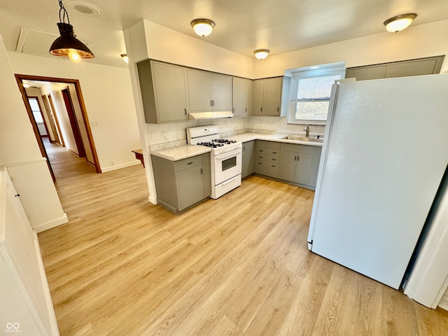 kitchen with light countertops, gray cabinetry, a sink, light wood-type flooring, and white appliances