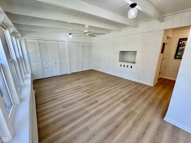 interior space featuring brick wall, two closets, wood finished floors, and beam ceiling