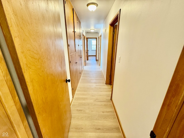 hall featuring light wood-style floors and baseboards