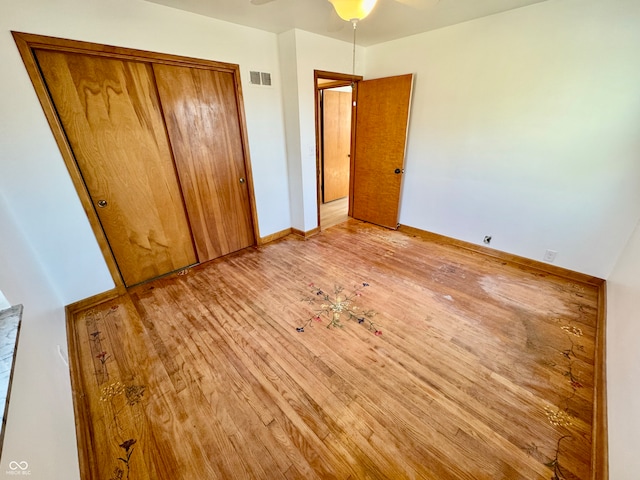 unfurnished bedroom featuring hardwood / wood-style floors, a closet, visible vents, and baseboards