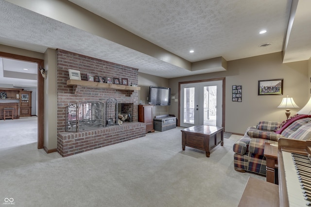 carpeted living area with a textured ceiling, a fireplace, visible vents, baseboards, and french doors