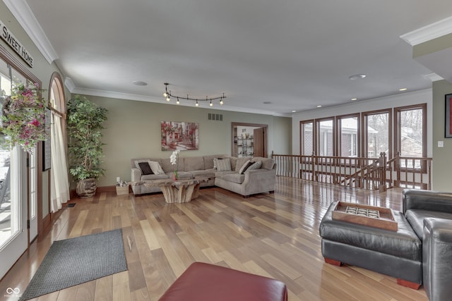 living room featuring a healthy amount of sunlight, wood finished floors, and crown molding