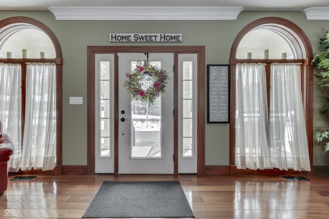 foyer entrance featuring ornamental molding, visible vents, and wood finished floors