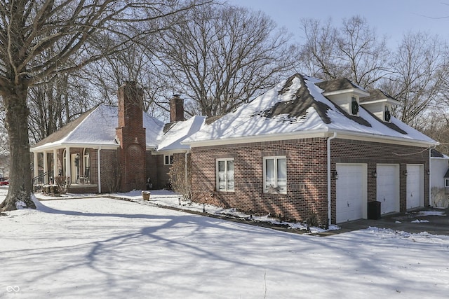 view of snow covered exterior featuring a porch and brick siding