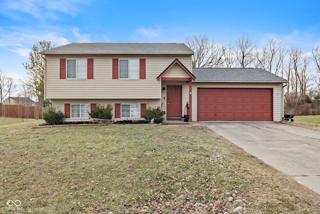 tri-level home with a garage, concrete driveway, fence, and a front lawn