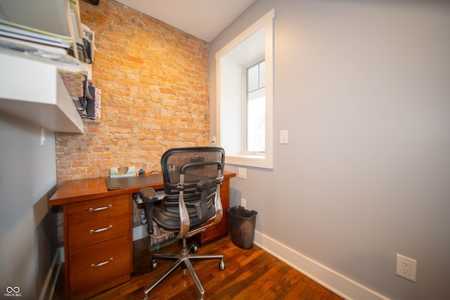 office space featuring brick wall, dark wood-style flooring, and baseboards