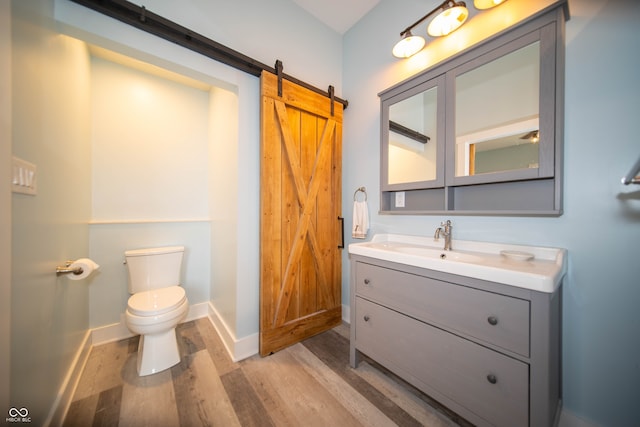 half bathroom featuring baseboards, vanity, toilet, and wood finished floors