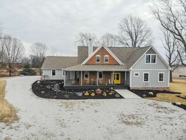 view of front facade featuring gravel driveway, a chimney, board and batten siding, and roof with shingles