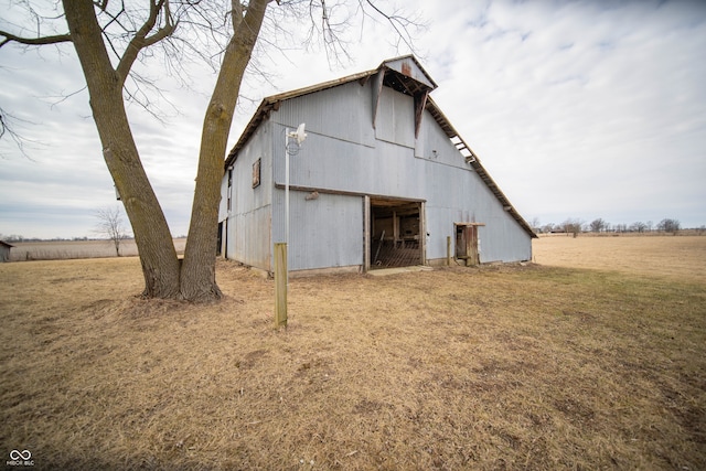 rear view of property with a barn, a garage, a lawn, and an outbuilding