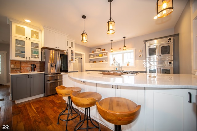 kitchen with stainless steel appliances, dark wood-style flooring, hanging light fixtures, open shelves, and tasteful backsplash