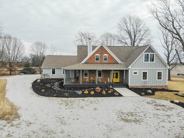 view of front of house with covered porch, a shingled roof, a chimney, and board and batten siding