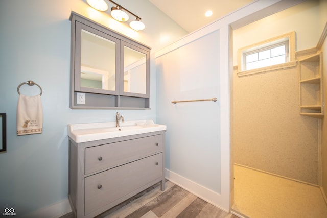 bathroom with recessed lighting, wood finished floors, vanity, and baseboards