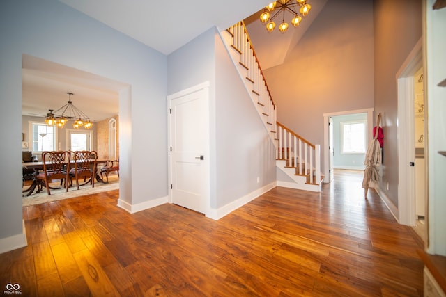 interior space featuring dark wood finished floors, a notable chandelier, stairway, a high ceiling, and baseboards