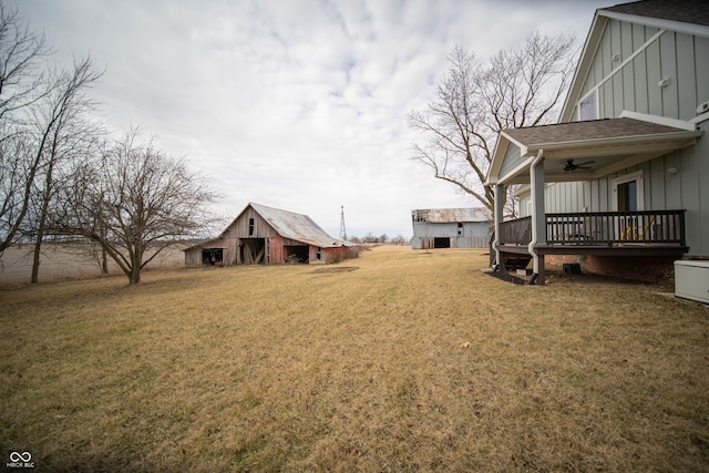 view of yard featuring an outdoor structure, a barn, and a ceiling fan