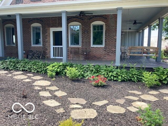 entrance to property featuring a porch and brick siding