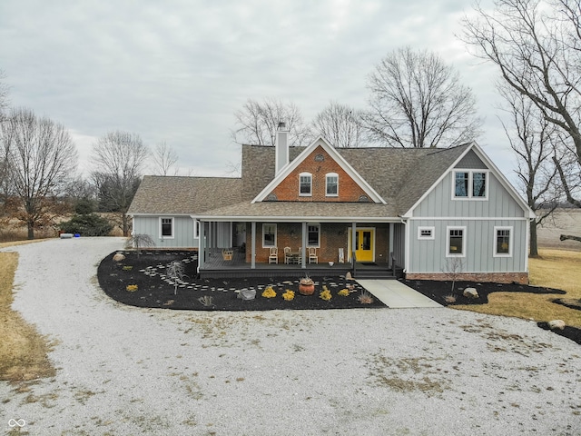 rear view of house featuring a porch, a shingled roof, driveway, board and batten siding, and a chimney