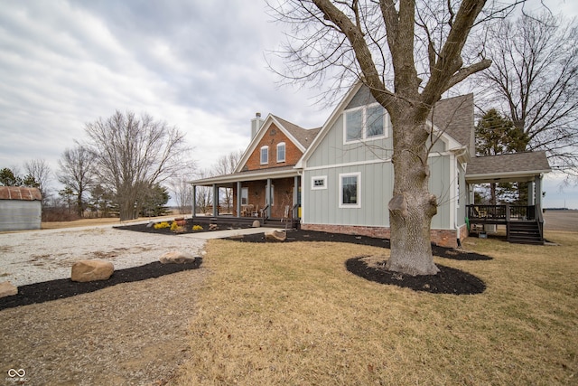 view of front of property with a chimney, roof with shingles, covered porch, board and batten siding, and a front yard