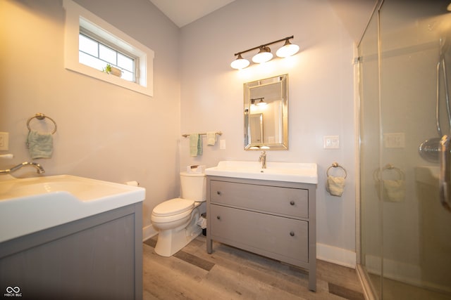 bathroom with toilet, wood finished floors, a shower stall, and vanity