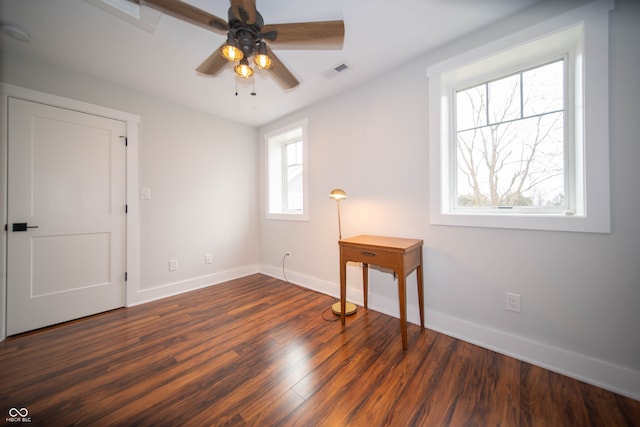 unfurnished room with dark wood-style floors, visible vents, ceiling fan, and baseboards