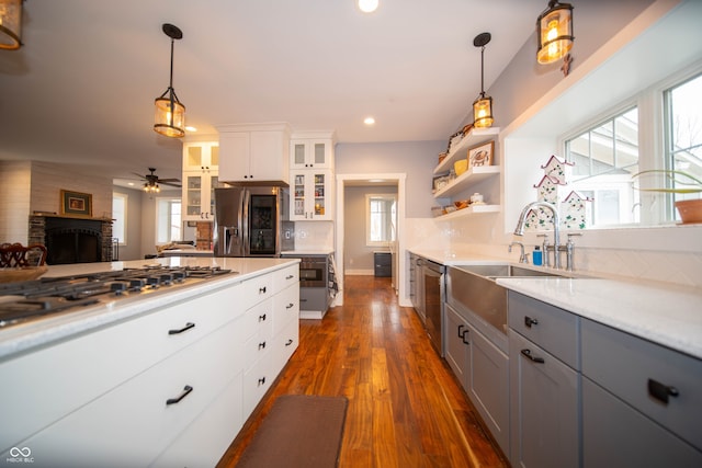 kitchen with appliances with stainless steel finishes, gray cabinets, dark wood-style floors, and tasteful backsplash