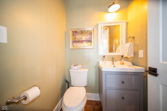 half bath featuring toilet, baseboards, and vanity