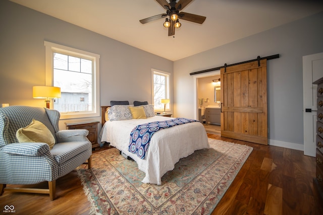 bedroom featuring a barn door, a ceiling fan, ensuite bath, wood finished floors, and baseboards