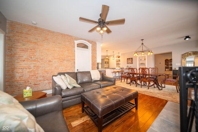 living area with brick wall, hardwood / wood-style floors, and a ceiling fan