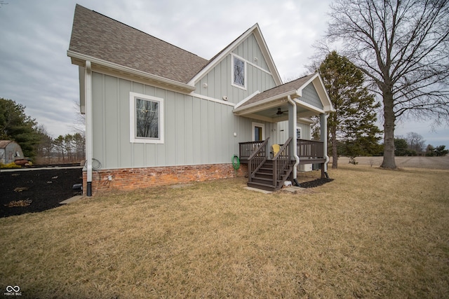 view of front of house featuring a front yard, a ceiling fan, board and batten siding, and roof with shingles