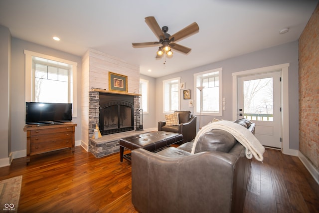 living area with dark wood-style floors, plenty of natural light, a fireplace, and baseboards