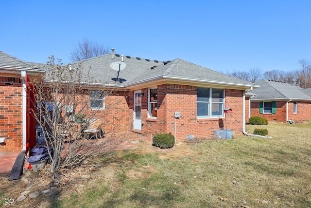 rear view of house with crawl space, a yard, brick siding, and a shingled roof