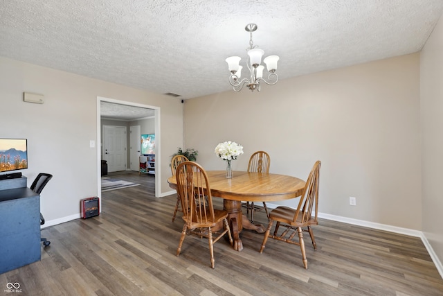 dining space with a chandelier, a textured ceiling, baseboards, and wood finished floors