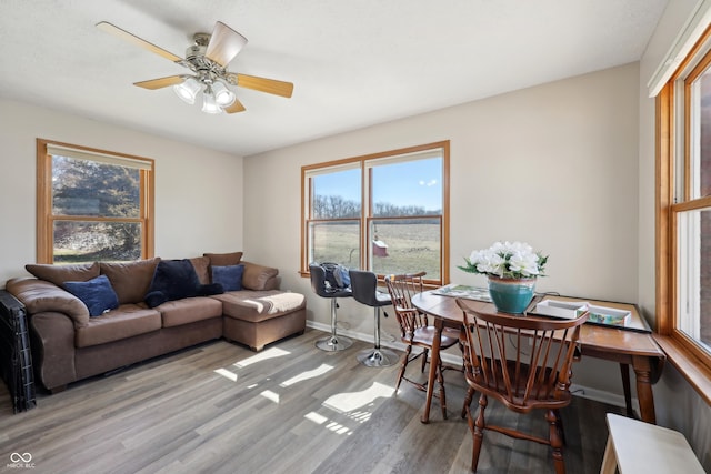 living area with wood finished floors, baseboards, and ceiling fan