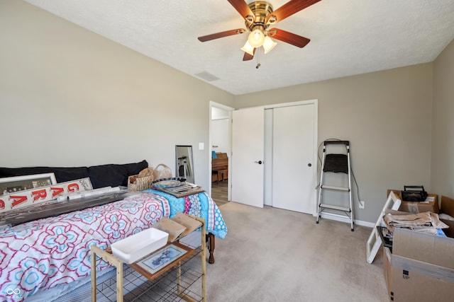 bedroom with a ceiling fan, visible vents, a closet, a textured ceiling, and light colored carpet