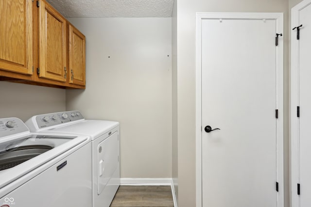 laundry area with cabinet space, a textured ceiling, baseboards, and separate washer and dryer