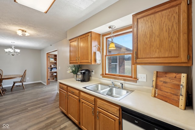 kitchen with light wood-style flooring, a sink, light countertops, a textured ceiling, and decorative light fixtures