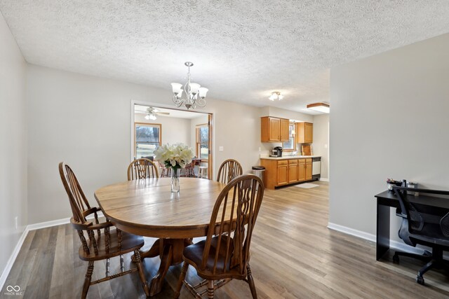 dining room featuring light wood finished floors, a textured ceiling, baseboards, and an inviting chandelier