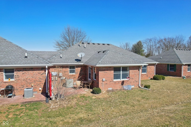 rear view of property with brick siding, a shingled roof, central AC, a yard, and a patio