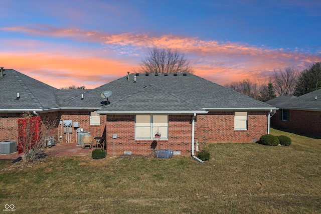 rear view of house featuring a yard, a patio, brick siding, and roof with shingles