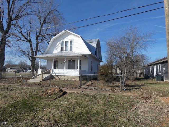 dutch colonial featuring covered porch, a fenced front yard, metal roof, and a gambrel roof